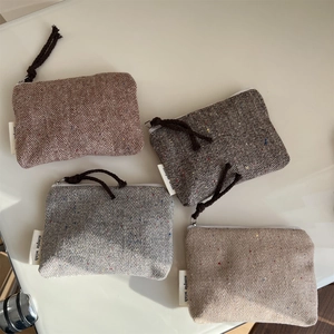 Mini herringbone tweed pouches in four colors with zipper closure and woven pull tags