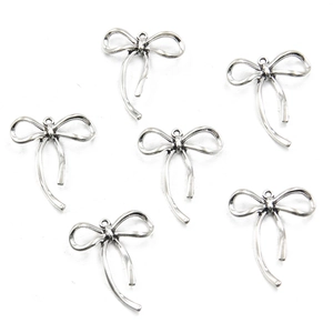 Detailed view of six silver alloy hollow bow pendants for DIY jewelry making and crafts