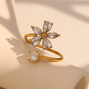 Gros plan d'une bague fleur plaquée or 18K avec zircons blancs sur support beige