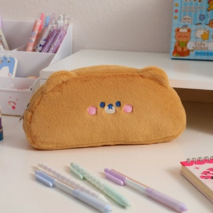 Macro shot of fluffy brown plush pencil case with cute bear face embroidery details