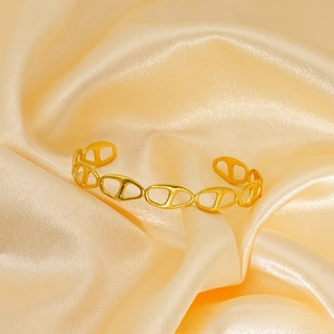 Detail of gold open cuff bracelet featuring classic anchor link chain design elements