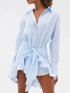 Detail of light blue linen shirt dress featuring waist tie knot and asymmetrical hem