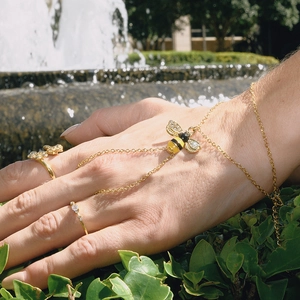 Detailaufnahme des goldenen Bienen-Fingerarmbands mit Kristallen an der Hand eines Models