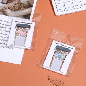 Detail of MOM crown heart watch strap charms in pink and blue jewelry packaging