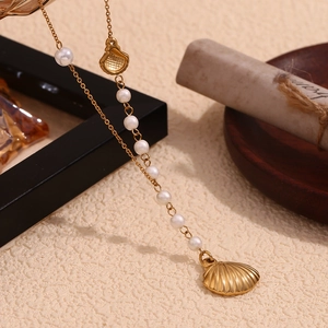 Detail of 18K gold-plated shell pendant and pearls on a minimalist chain necklace