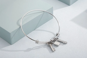 Detailed close-up of a silver stainless steel bangle with star lock and key charms