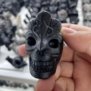 Detailed view of hand-carved black obsidian skull sculpture with feather decorations