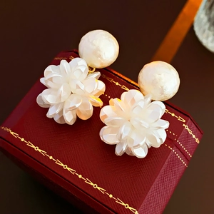 Close-up of white flower earrings with pearls on a red luxury jewelry gift box