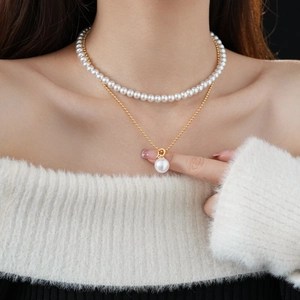 Detail of double-layer gold plated necklace with pearls on a white sweater model