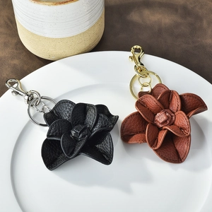 Elegant leather camellia flower keychains in black and brown on white plate