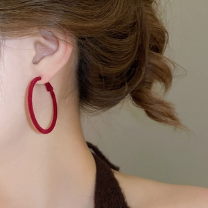 Close-up of elegant red flocked hoop earrings for women with velvet texture