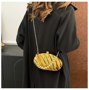Detail of gold oval evening bag with vertical texture worn with a black coat