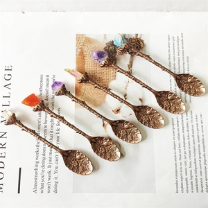 Detail view of 6 vintage bronze spoons with branch handles and colorful raw crystals