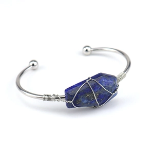 Detail of silver wire-wrapped open cuff bracelet with blue lapis lazuli raw gemstone