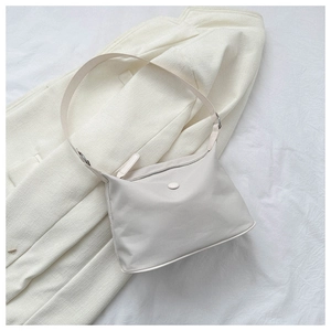 Minimalist cream white Oxford cloth shoulder bag detail on textured fabric background