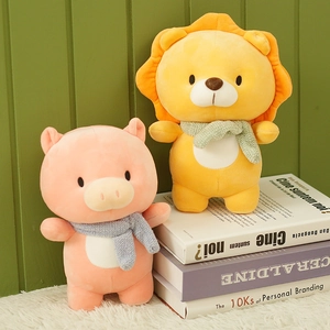 Cute plush lion and pig stuffed animals wearing knit scarves on a bookshelf