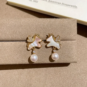 Vue macro des boucles d'oreilles licorne dorées avec zircon et perles nacrées pendantes