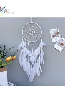Close-up of white feathers and woven web detail on a bohemian dream catcher ornament