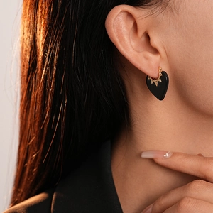Gros plan de la boucle d'oreille cœur noir avec motif soleil doré sur mannequin