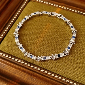 Dettaglio di un bracciale in argento con zirconi blu e maglie a X in scatola regalo