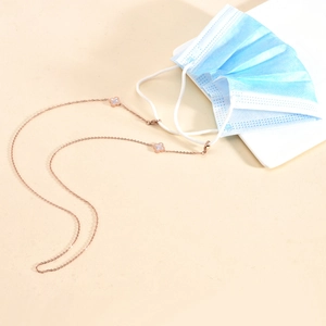 Detail of rose gold mask chain with white clover charms attached to a face mask