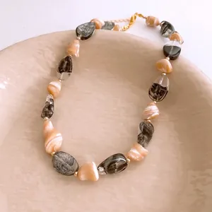 Collier de perles irrégulières en marbre rose et gris avec fermoir doré sur plateau