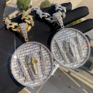 Close-up of gold and silver hip hop pendants with zircon cross held in a hand