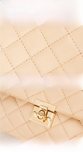 Detail of beige quilted leather texture and golden metal square clasp on the shoulder bag