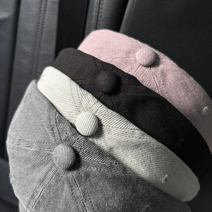 Close-up of four colored baseball caps showing cotton twill fabric and top button detail