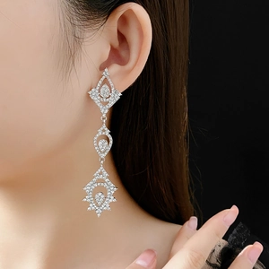 Detail of luxury silver drop earrings with inlaid zircons worn on a model against black