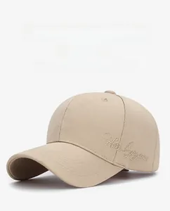 Dettaglio del ricamo dorato Hello Gorgeous su un berretto da baseball in cotone beige