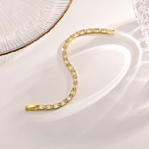 Makroaufnahme eines flexiblen goldenen Tennisarmbandes mit Zirkonia im Rechteckschliff