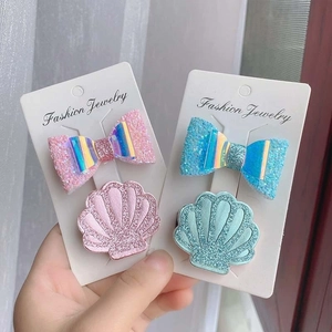 Close-up of pink and blue glittery bow and shell hair clips for girls on display cards