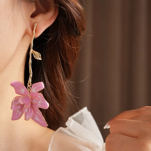Close-up of pink flower earrings with gold stem on model with natural lighting