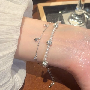 Detail view of stacked pearl bead bracelet with silver star pendant and zircon spheres