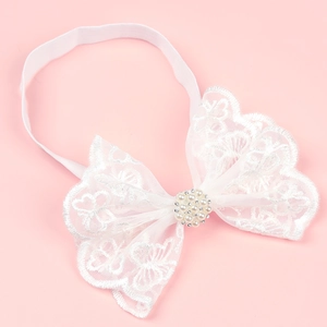 Close-up of white lace baby headband with pearl and rhinestone bow on pink background