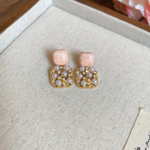 Macro shot of pink geometric studs with pearls and small crystals on cream fabric