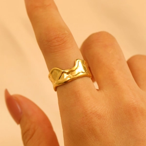 Macro shot of gold irregular wavy textured stainless steel ring on model finger