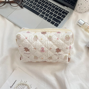 Close-up of quilted white cosmetic bag with cute animal prints on a desk setup