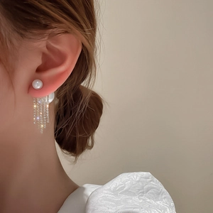 Elegant pearl stud earring with long sparkling diamond tassel on model's ear