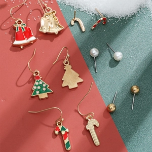 Detail shot of Christmas earring set with gold bells, trees and canes on festive background