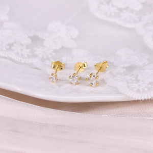 Detailed close-up of gold star earrings set with crystals on a white lace tray