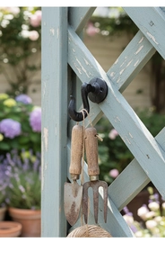 Close-up of vintage black cast iron garden hook with gardening tools and hydrangea