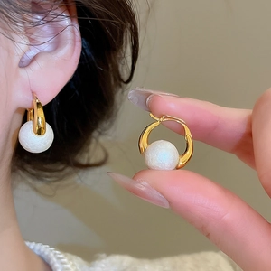 Detail of vintage gold plated hoop earrings featuring a large textured white pearl bead