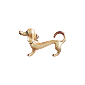 Cute gold enamel dachshund brooch with green rhinestone eye on a white background
