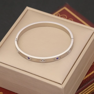 Macro shot of silver evil eye bangle with blue stones in a beige jewelry box