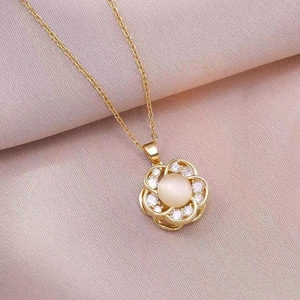 Close-up of golden spinning flower necklace pendant with white gemstone and zircons