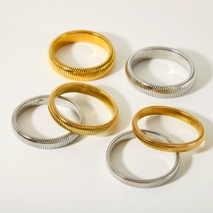 Elastic stainless steel snake chain bracelets in gold and silver finishes on beige surface