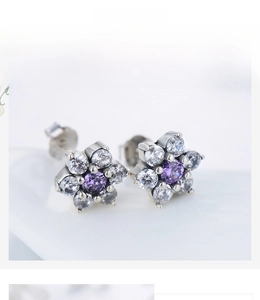 Macro detail of S925 sterling silver flower stud earrings with purple and white crystals