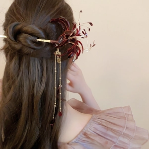 Close-up of red lycoris hair stick with golden tassels worn on hair in detailed view
